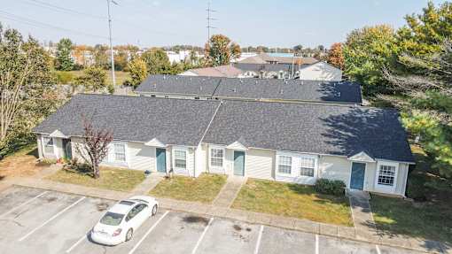 A white house with a grey roof and a car parked in front.