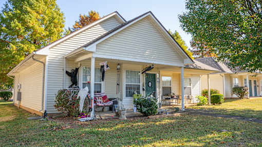 A white house with a porch and a lawn in front.