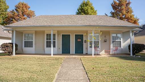 A small house with a green door and white siding.