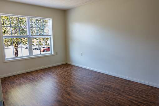 A room with a window and wooden flooring.