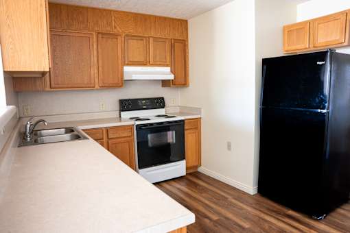 A black refrigerator sits in a kitchen with wooden cabinets.