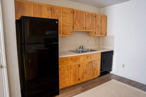 A black refrigerator sits in a kitchen with wooden cabinets.