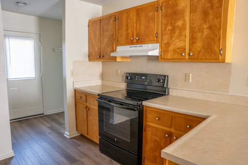 A kitchen with wooden cabinets and a black oven.