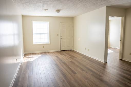 A room with wooden floors and a window letting in sunlight.