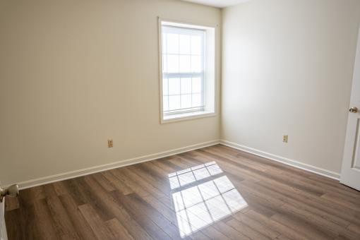 A room with a window and wooden flooring.
