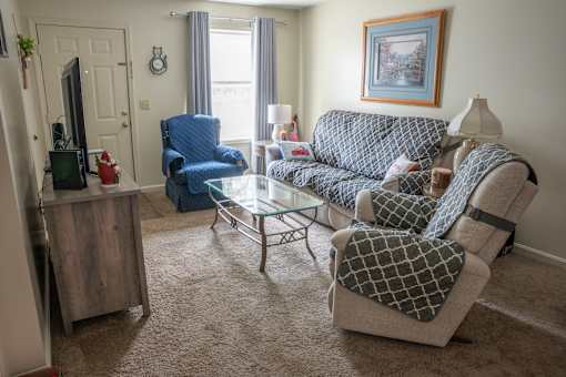 A living room with a blue chair and a grey couch.