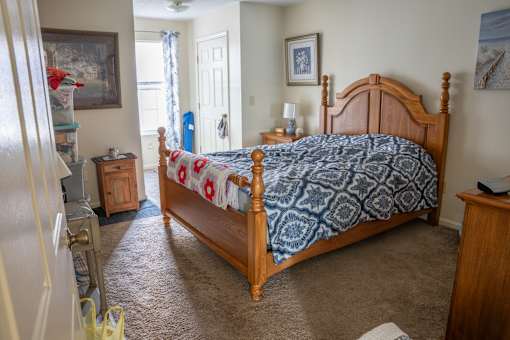 A bedroom with a bed, dresser, and a painting on the wall.