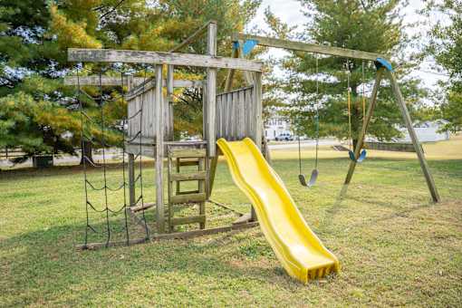 A playground with a yellow slide and a wooden structure.