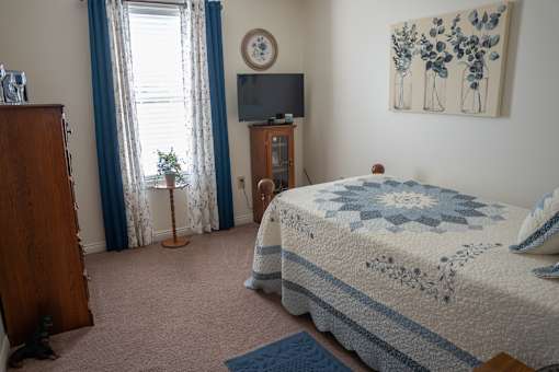 A bedroom with a bed, a dresser, a nightstand, and a painting on the wall.