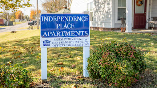A sign for Independence Place Apartments is in front of a house.