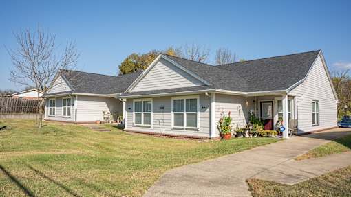 A house with a grey roof and white walls with a small front yard.
