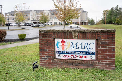 A brick sign for MEN'S ADDICTION RECOVERY CAMPUS with a phone number on it.