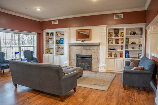 A living room with a fireplace and two grey couches.