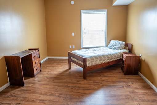 A bedroom with a bed, dresser, and nightstand.
