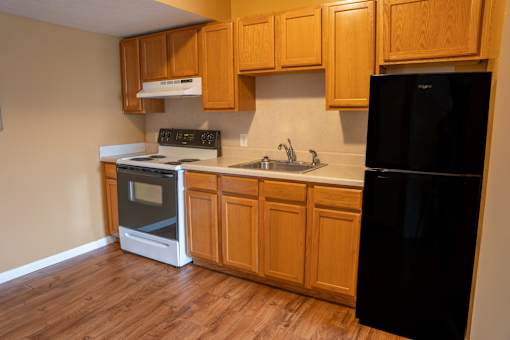 A black refrigerator sits in a kitchen with wooden cabinets.