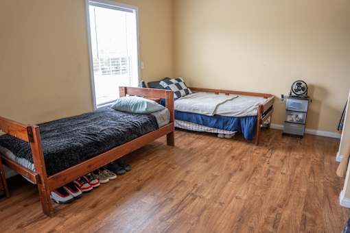 A bedroom with two beds and a wooden floor.