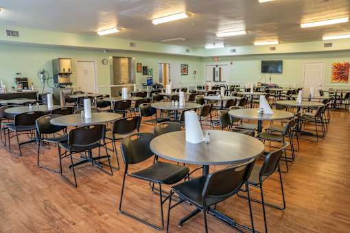 A room with tables and chairs and a clock on the wall.