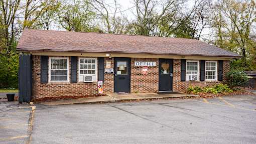 A small brick building with a black door and windows.