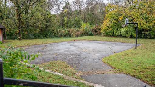 A basketball court surrounded by trees and grass.