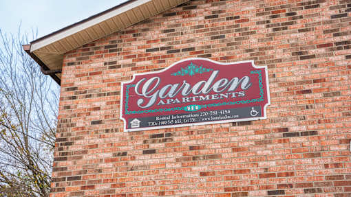 A sign on a brick wall that says Garden Artments.