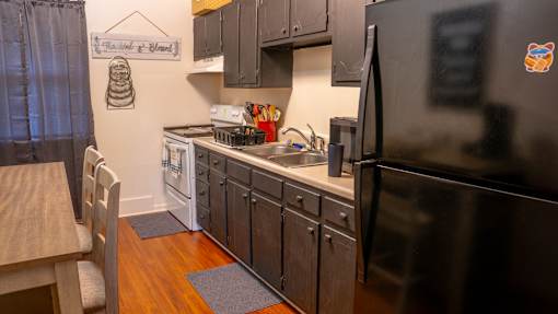A kitchen with a black refrigerator and wooden floors.