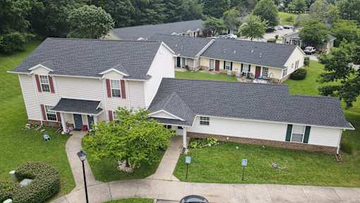 A large white house with a grey roof and a green lawn in front.