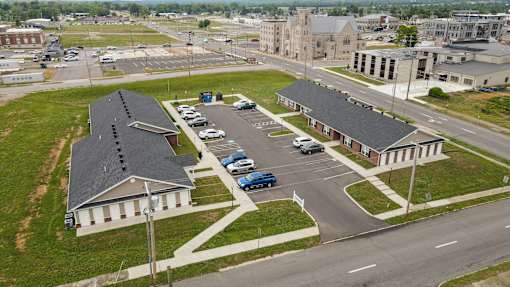A parking lot with cars and a building with a black roof.