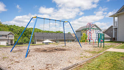 A playground with a blue swing set and a red and yellow climbing structure.