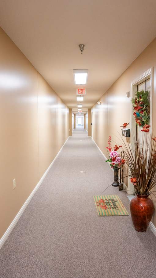 A long hallway with a red vase and a green mat on the floor.
