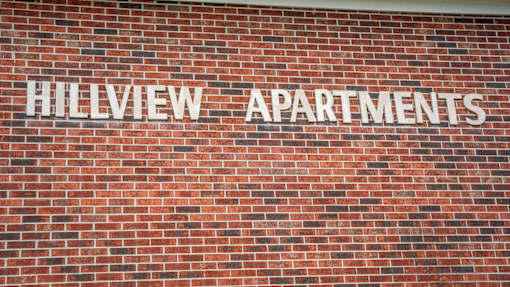 Hillview Apartments sign on a brick wall.