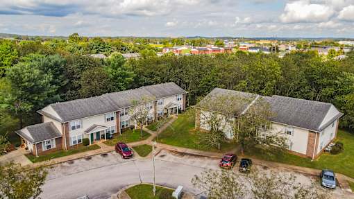 A bird's eye view of a residential area with two houses and cars parked in front.