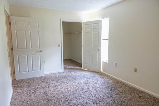 A room with a carpeted floor and two white doors.