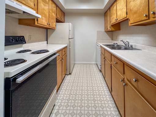 A kitchen with a black stove top oven and wooden cabinets.