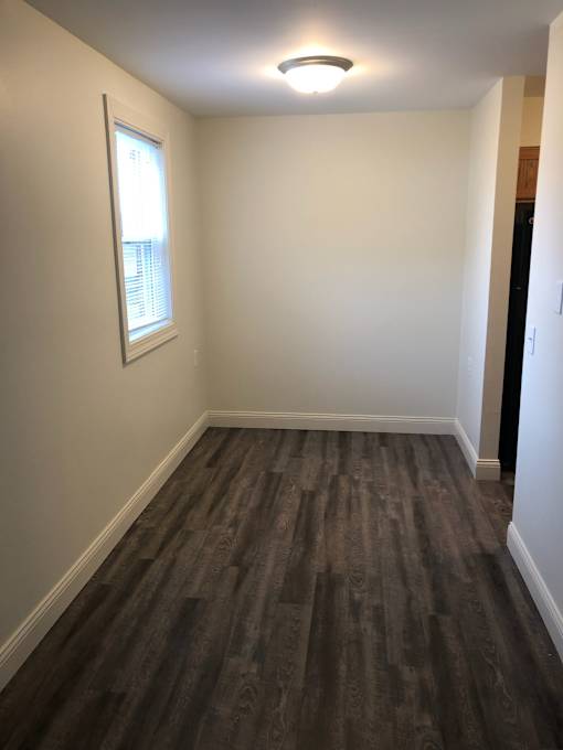 A room with a window and a wooden floor.