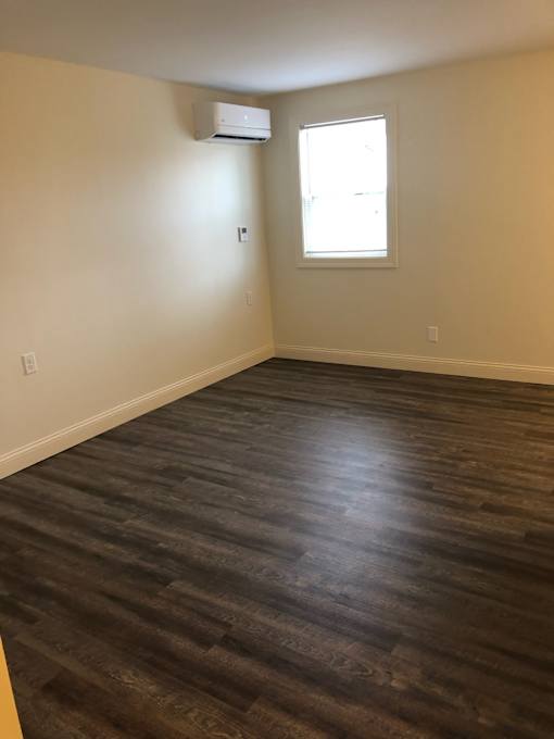 A room with a window and a wall-mounted air conditioner unit.