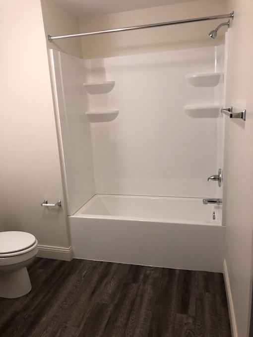A white bathroom with a toilet and a walk in shower.