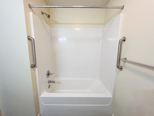 A white bathtub with silver grab bars on the side.