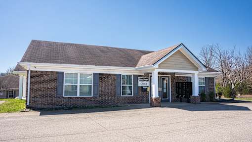 A small brick building with a brown roof and a sign that says "OFFICE" on it.