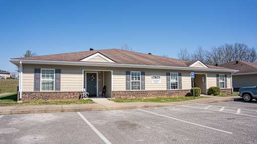 A small building with a parking lot in front.