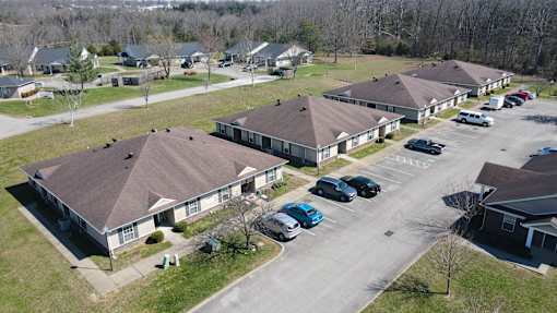 A parking lot with cars and houses in the background.
