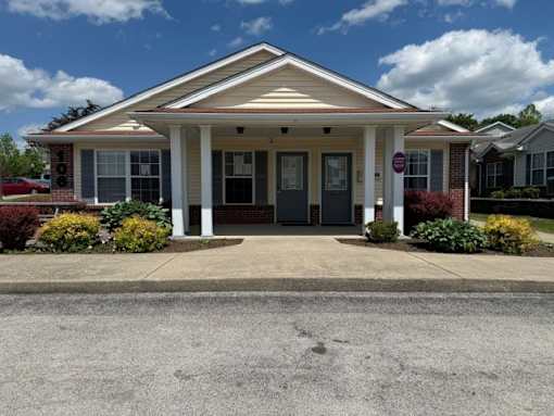 A small building with a porch and a sign on the right side.