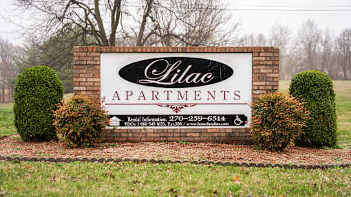 A sign for Hilac Apartments with a phone number and website listed.
