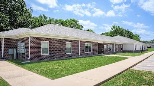 A brick building with a white roof and a long walkway in front.