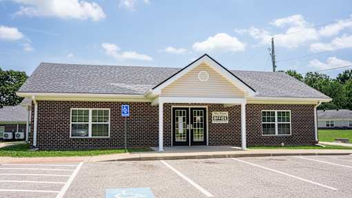A small building with a parking lot in front of it.