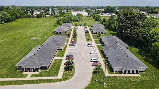 A parking lot is in front of a building with a grey roof.