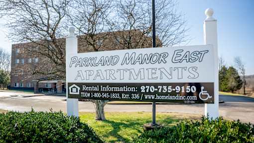 A sign for Parkland Manor East Apartments with rental information.