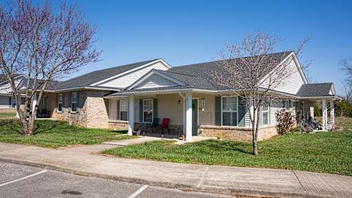 A house with a white front porch and a tree in front.