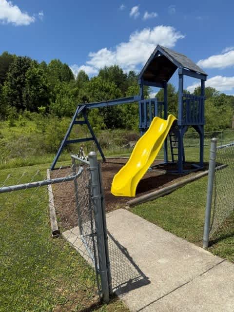 A playground with a yellow slide and a blue structure.