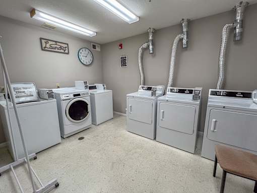 Laundry room with washers and dryers and a clock on the wall.
