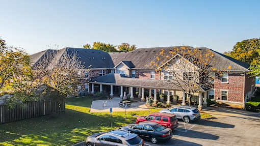 A large house with a carport and a parking lot in front.